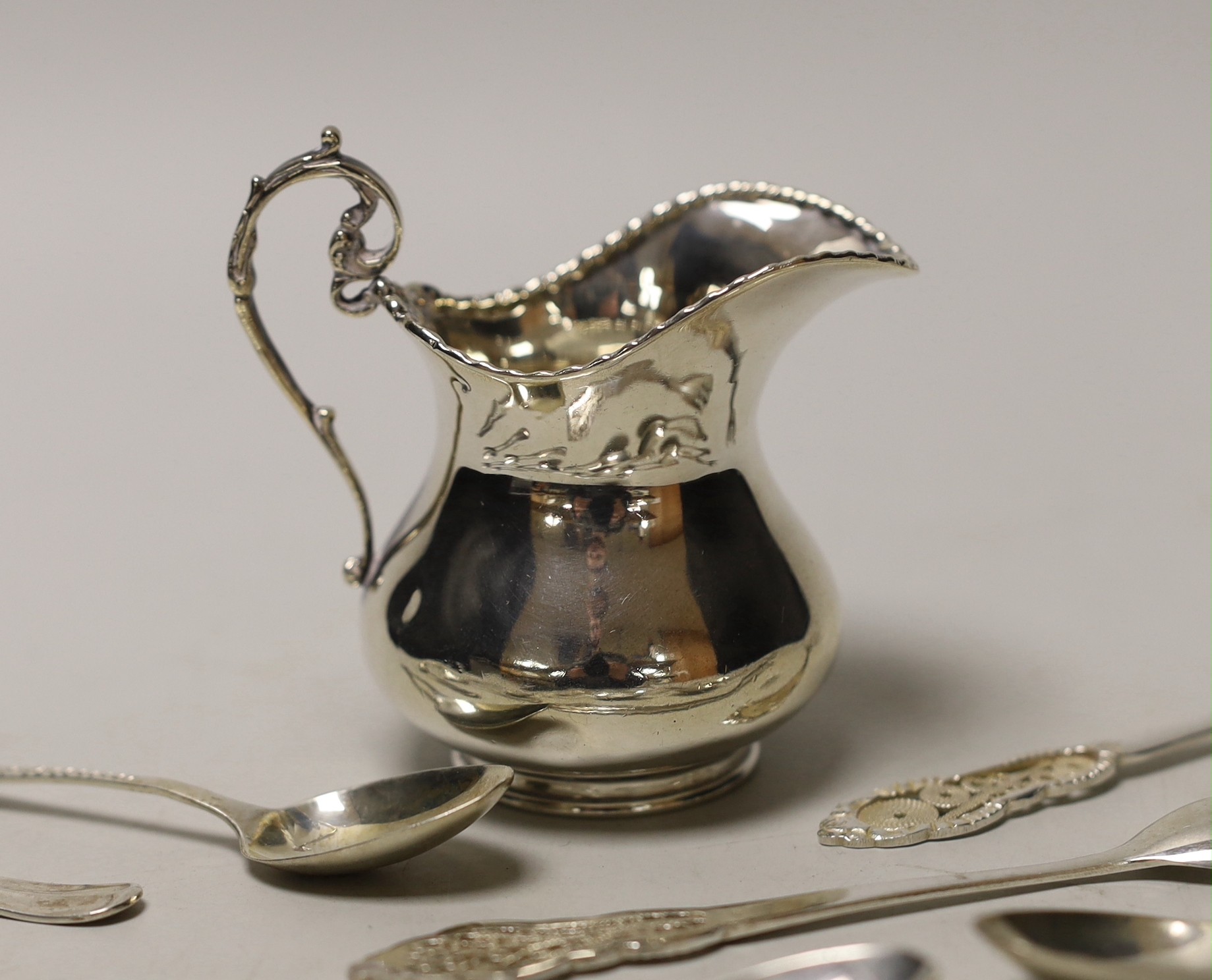 A silver cream jug and sundry minor spoons and forks.